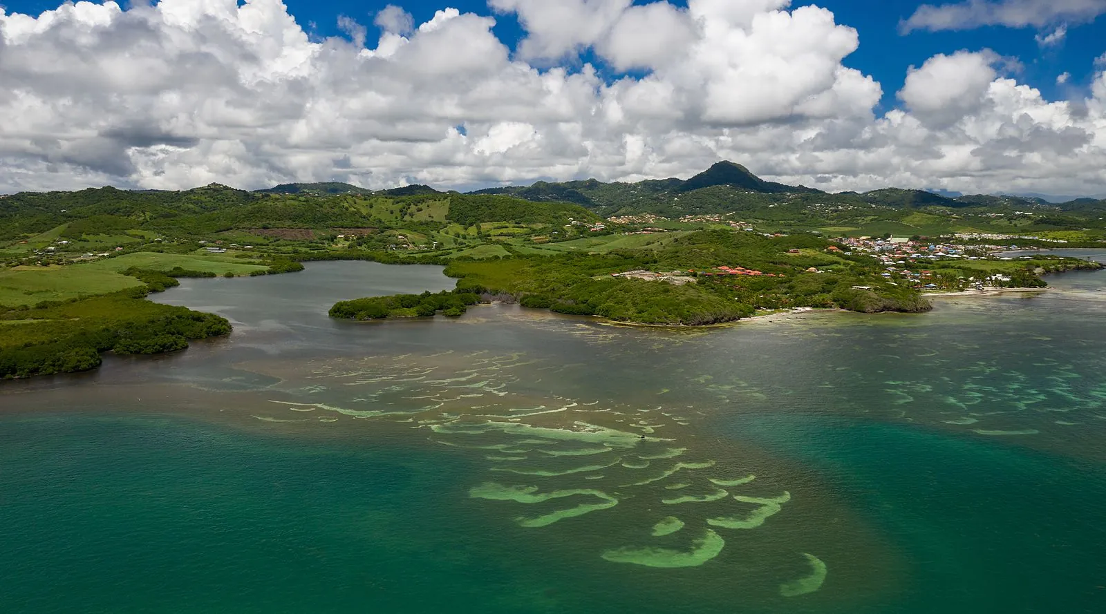 Vue aérienne large des fonds blancs découpés du François avec les mornes en arrière-plan, Martinique