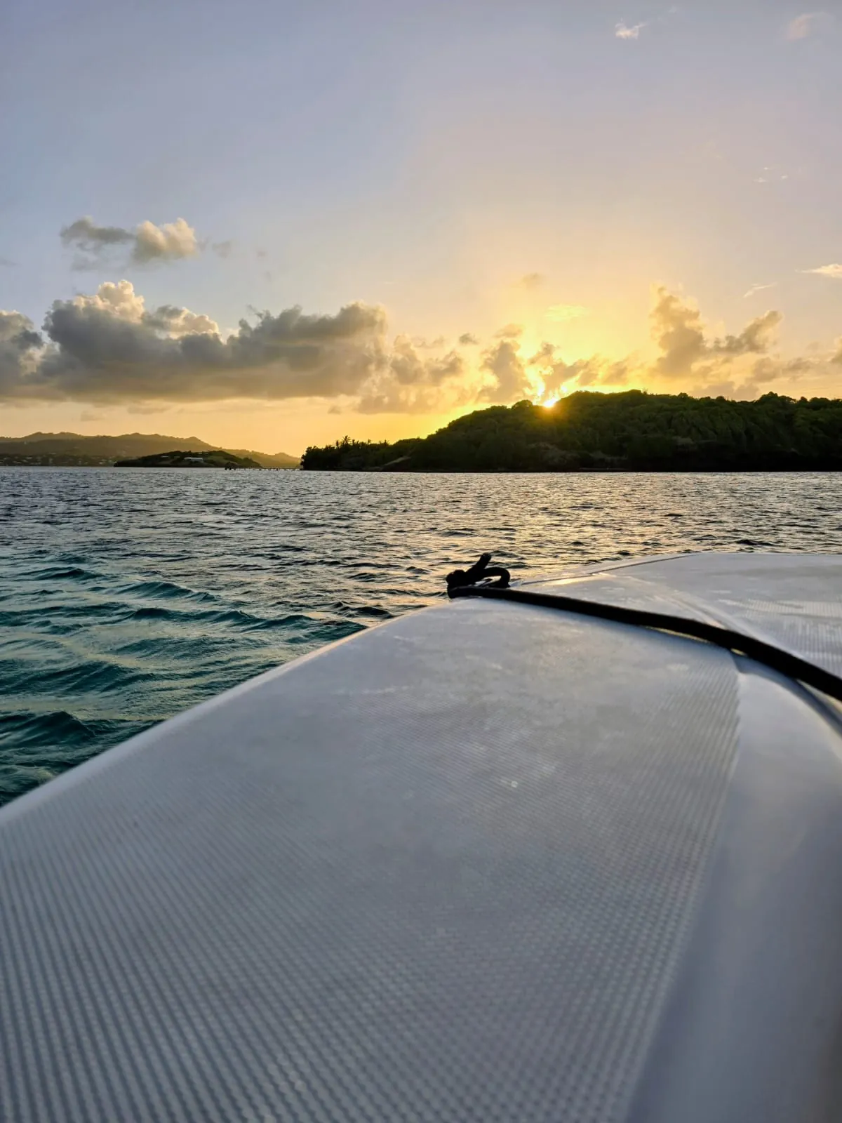 Coucher de soleil derrière un îlet boisé, vu depuis le plat-bord d'un bateau, Martinique